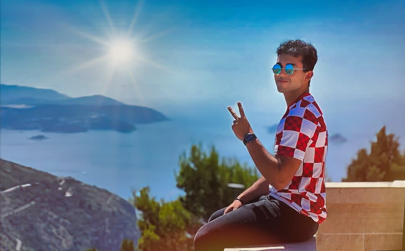 Sitting above a sunlit coastline, two fingers raised